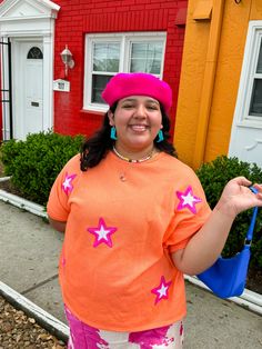 Bring on the glitz and glam with this oversized tee! This orange tee features pink stars that make you feel like a super star!!! Keep it casual with a pair of jeans or colorful pants, or dress it up with a pink skirt! This tee looks great with pinks, yellows, and blues! Oversized fit Style with jeans, colorful pants, or a cute skirt! This shade of orange looks great with pinks, blues, and yellows! True to size with an oversized fit 50% POLYESTER 37% COTTON 13% RAYON Imani is 5'3 and wearing a si Colorful Pants, Orange Star, Orange Tees, Pink Power, Rainbow Shop, Colored Pants, Neutral Outfit, Super Star, Pink Stars