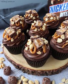 chocolate cupcakes with peanut butter and pretzel toppings on a wood slice