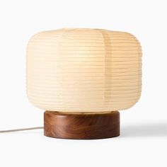 a lamp that is on top of a wooden base and has a white paper shade over it