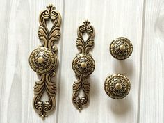 an assortment of antique door knobs and pulls on a white wooden surface with wood grain