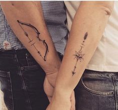 two people holding hands with tattoos on their arms