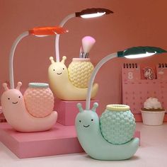 three snail lamps sitting on top of a pink shelf