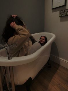 a woman sitting in a bathtub with her hair hanging back