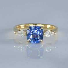 a yellow gold ring with a blue sapphire and three diamonds