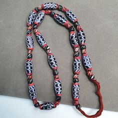 a red string with black and white designs is attached to a long beaded necklace