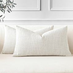 two pillows sitting on top of a white couch