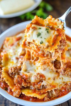 a white bowl filled with lasagna sauce and topped with cheese, meat and parmesan