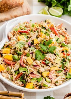 a white bowl filled with rice salad next to chopsticks and lime wedges