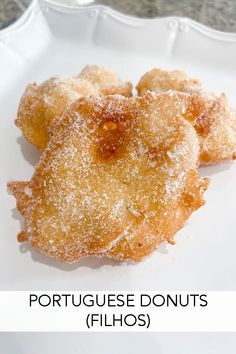 three donuts on a white plate with sugar sprinkled over them and the words portuguese donuts filos