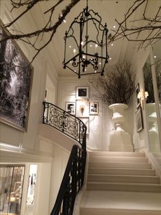 an elegant staircase with chandelier and pictures on the wall