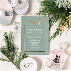 wedding stationery with pine branches and greenery on the table, surrounded by silverware