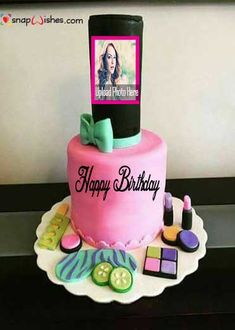 a pink birthday cake with a photo on the top and other items around it,