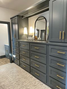 a large gray dresser with gold handles and drawers in a living room next to a mirror