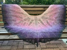 a knitted shawl sitting on top of a wooden bench