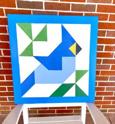 a blue and white quilt sitting on top of a wooden chair next to a brick wall