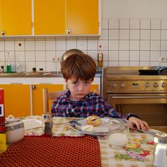 a young boy sitting at a kitchen table eating food