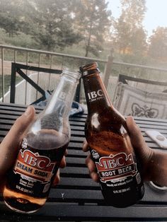 two people holding beer bottles on top of a table