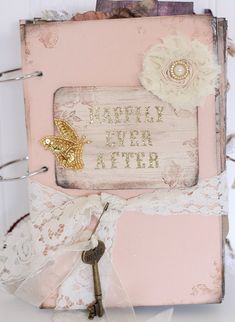 an altered book with a key on the front and some ribbons around it, sitting on a table