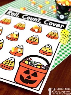 a halloween themed roll and cover game with candy in a pail on the table