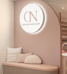 the interior of a nail salon with pink walls and white furniture, along with a circular sign that reads diamond nails & spa