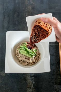 someone is pouring sauce on some noodles in a bowl