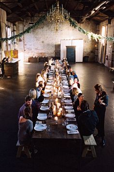 a long table is set up with plates and candles for an event or gathering in the warehouse