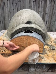 a person is making a helmet out of wood and cement on top of a table