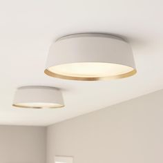 two circular lights are hanging from the ceiling in a room with white walls and flooring