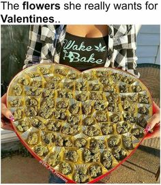 a woman holding a heart shaped plate full of cookies and candy bars with the caption that reads, the flowers she really wants for valentine's bake