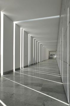 an empty hallway with white walls and columns