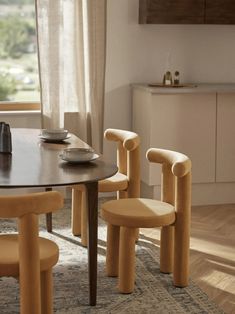 a dining room table with four chairs and a bowl on top of it in front of a window