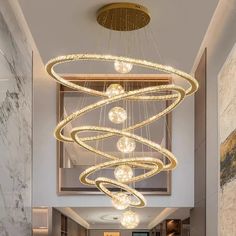 a modern chandelier hanging from the ceiling in a lobby with marble walls and flooring