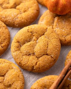 pumpkin spiced cookies on a baking sheet with cinnamon sticks and an apple in the background