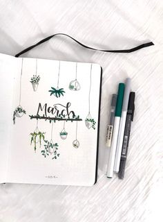 an open notebook with the word march written on it next to some markers and pens