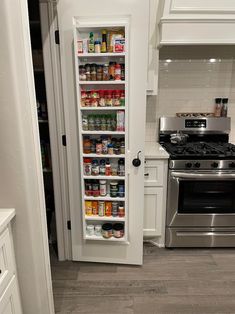 an open pantry door in the middle of a kitchen with stainless steel appliances and white cabinets