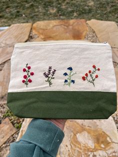 a hand holding a small pouch with flowers on it