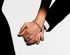 two people holding hands with rings on their fingers and bracelets around their wrists, against a white background