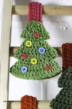 a crocheted christmas tree hanging from a wooden ladder with buttons on the top