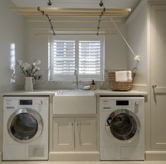 a washer and dryer in a white laundry room with blinds on the window