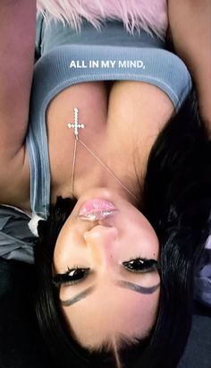 a woman with black hair and piercings laying down