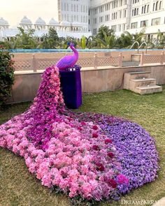 a peacock sitting on top of a pile of purple and pink flowers next to a pool