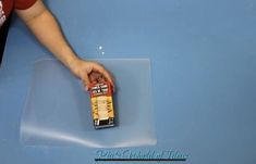 a person holding a can of beer on top of a blue table