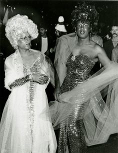 two women dressed up in costumes and headdresses at a party with other people