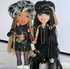 two dolls dressed in black and white are standing next to each other with long hair