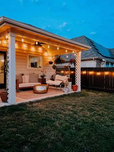 an outdoor living area with patio furniture and string lights on the ceiling is lit up at night