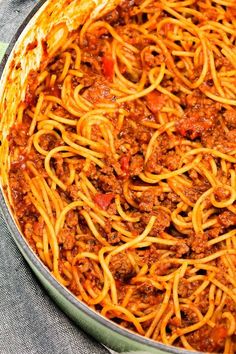 a pan filled with spaghetti and meat sauce on top of a cloth covered tablecloth