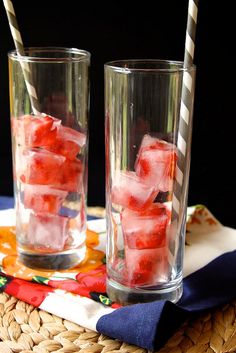 two glasses filled with ice and strawberries on top of a blue and white plate