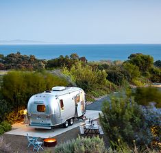 an rv parked on the side of a road next to some trees and bushes near water