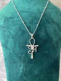 This elegant necklace features a stunning pendant combining two of the most iconic symbols of ancient Egypt: the Ankh and the Eye of Horus. Crafted from high-quality sterling silver, the pendant showcases an intricate design that includes the Eye of Horus set within the loop of the Ankh. The necklace is complemented by a delicate chain adorned with small, evenly spaced beads, adding a touch of sophistication to this unique piece. Perfect for anyone interested in Egyptian mythology or looking for Eye Of Horus Pendant, Eye Of Horus Jewelry, Eye Of Horus Necklace, The Eye Of Horus, Ankh Necklace, Iconic Symbols, Mystical Jewelry, Real Gold Jewelry, Egyptian Mythology