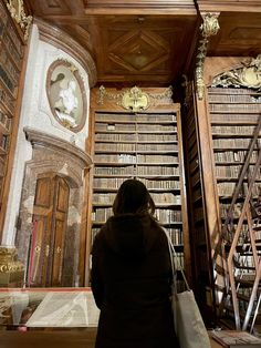 a woman standing in front of a library filled with books